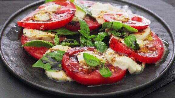 卡普雷沙拉配马苏里拉奶酪、番茄和罗勒叶装在黑色盘子里意大利美食