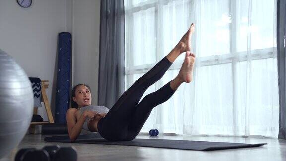 运动年轻的亚洲女性穿着运动服在家锻炼健身教练或普拉提教练在家里教授在线课堂锻炼或瑜伽课程