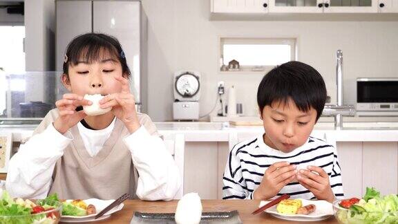 亚洲小孩在家吃饭团当早餐