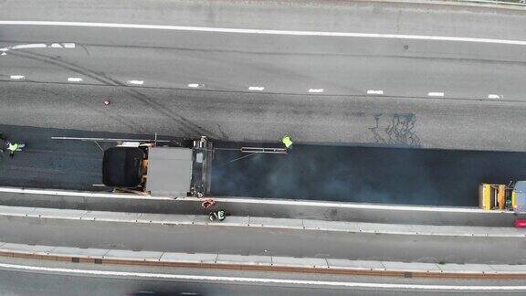 沥青摊铺机和蒸汽压路机在道路建设和维修工程中沥青和铺装过程中工人在新道路施工现场工作放置一层无人机