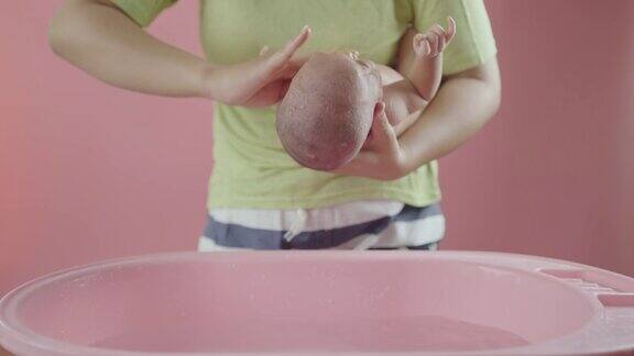 母亲脱衣服洗澡她儿子孤立的粉红色背景