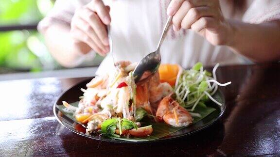 一名亚洲妇女在餐馆里吃着美味的海鲜沙拉