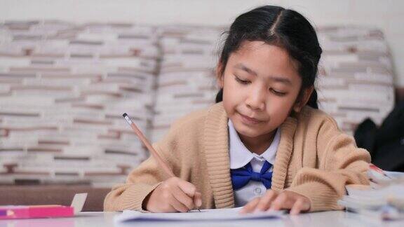 亚洲小女孩快乐地做作业泰国小女孩穿着幼儿园校服在家学习和教育