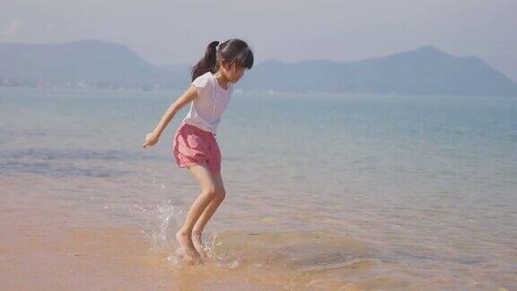 快乐年轻可爱的亚洲女孩在海滩上跑步然后在海上跳小男孩在沙滩上玩脸上带着幸福和微笑在海滩度假
