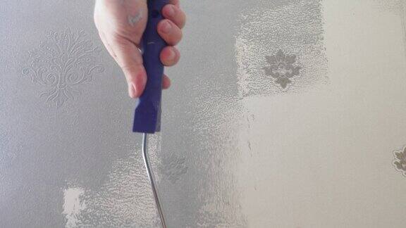 用滚筒和灰色油漆把旧墙纸刷在墙上
