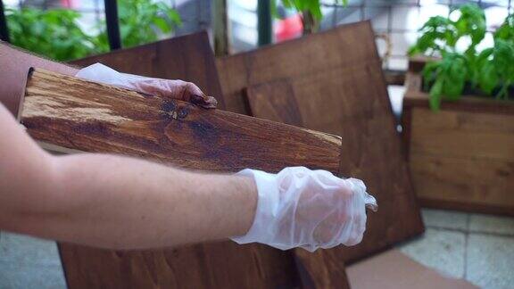 木匠在手套中修复木板表面工人用工业海绵抛光木材表面并涂上棕色污渍细木工涂覆木材以保护其免受破坏