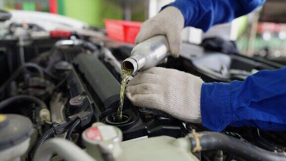 发动机清洁有助于提高发动机效率在汽车维修车间汽车机械技师近距离从铝瓶中倒入发动机冲洗以清理发动机系统(气缸和活塞)