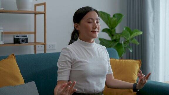 亚洲女性平静下来在家里用手做瑜伽的姿势深呼吸