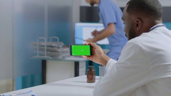 非裔美国专家医生看着模拟绿色屏幕色度键智能手机