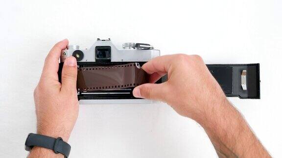 一名男子正在把35毫米胶卷装进老式相机