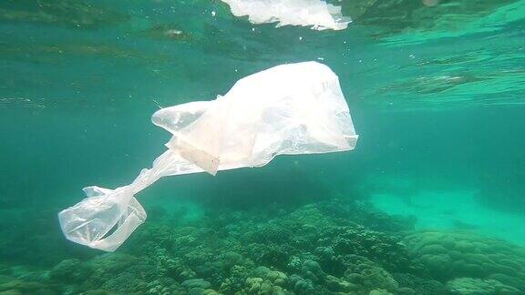 塑料袋漂浮在水下脆弱的珊瑚礁上