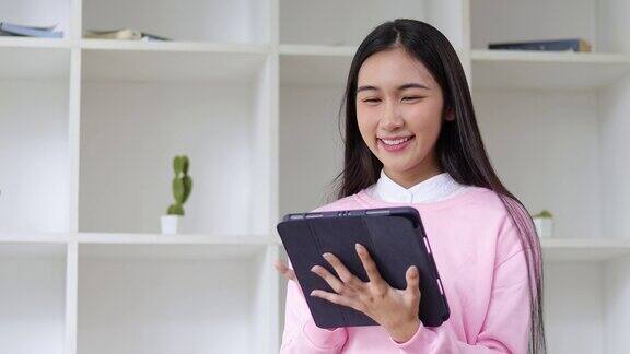 快乐的亚洲女人在家里玩平板电脑在线购物