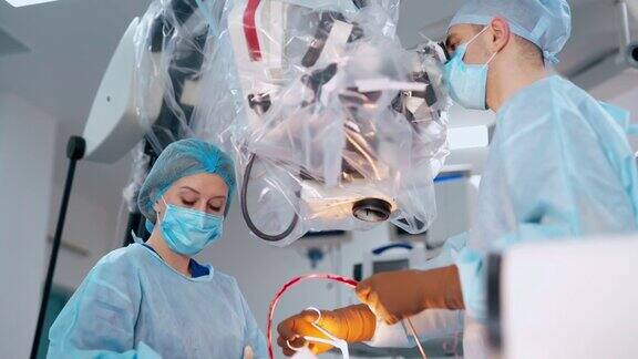 通过显微镜观察神经外科身着蓝色制服的医学专家在做手术医生在外科手术中使用现代设备