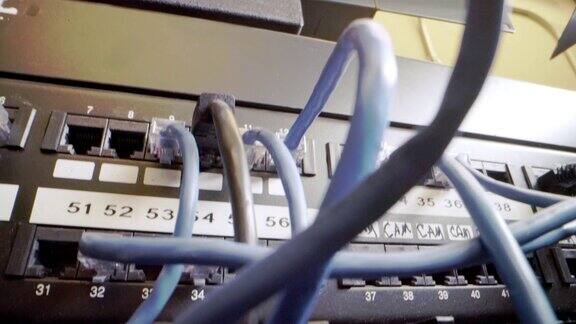 IT组网柜背景中插入交错的、杂乱的高速千兆因特网Cat5数据补丁线缆的闪烁网络交换机的Cat5e以太网线缆管理
