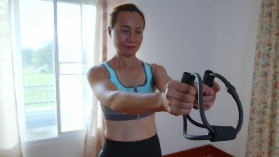 亚洲妇女伸展她的手臂与健身橡胶扩张器