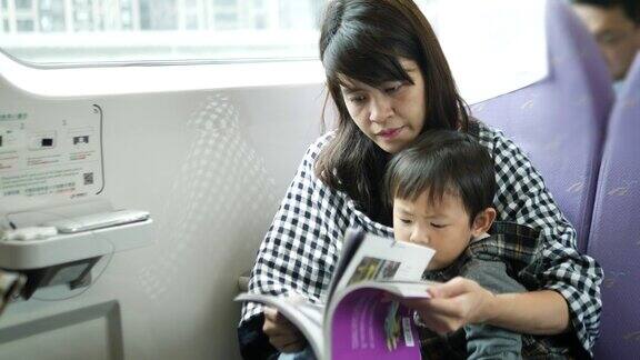 年轻的亚洲母亲和儿子在火车上看书