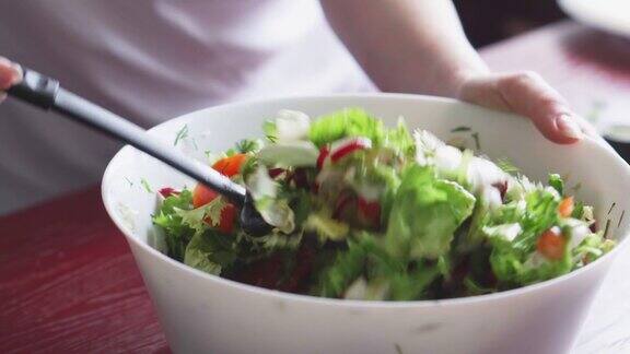 健康午餐的特写有萝卜、西红柿、生菜、香草和橄榄在厨房做健康的食物新鲜蔬菜沙拉素食主义者的饮食女人切拌沙拉