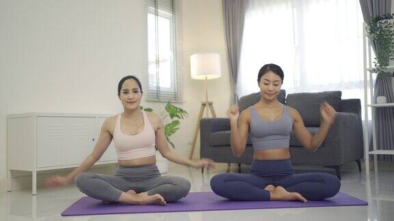 两个年轻的女人在客厅里练习瑜伽
