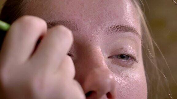 特写肖像年轻的白人女性化妆师应用黑色眼线上眼睑