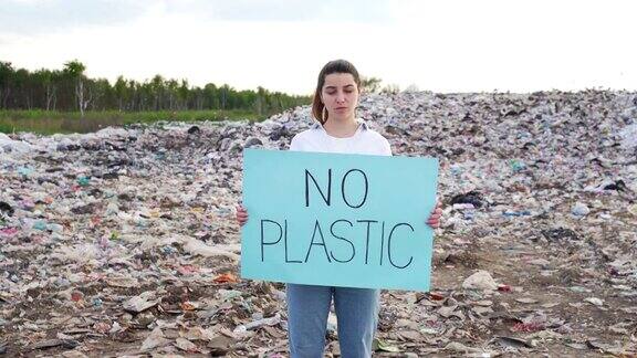 环保人士举着“禁止使用塑料”的海报女人或女孩站在一个大垃圾填埋场