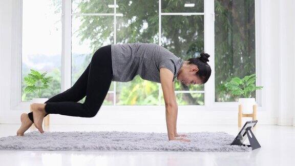 美丽的亚洲女性在家里的客厅做平板支撑运动训练健康在家