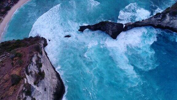 航拍海湾碧蓝的海水岩石峭壁和海浪碰撞