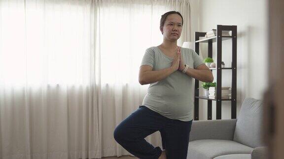 年轻的亚洲女子站在家里练习瑜伽