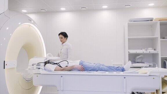 女医生控制核磁共振诊断仪移动试管内的男子