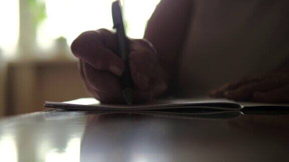一个老妇人坐在桌子上手写的特写