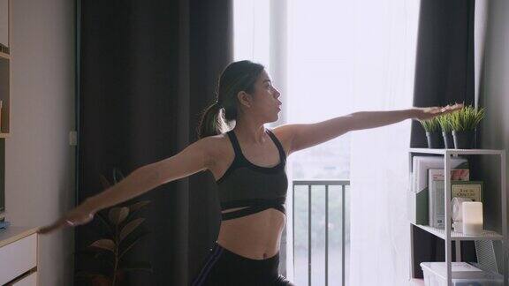 年轻的亚洲女子独自在她的公寓里做瑜伽