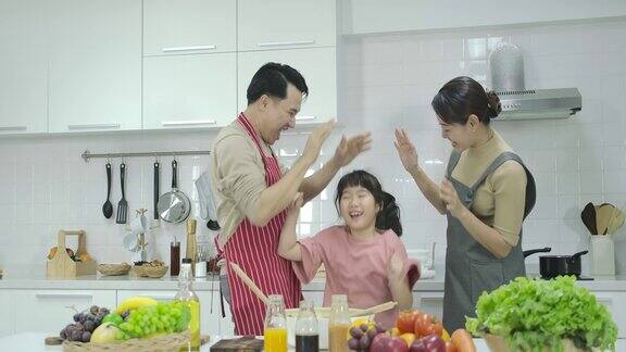 快乐快乐的亚洲家庭一起跳舞在厨房做饭