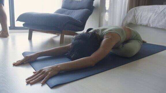 亚洲女性在瑜伽垫上伸展身体