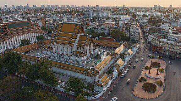 空中超低空无人机俯瞰泰国曼谷的WatSuthatThepwararam（SuthatThepwararam寺庙）和GiantSwing（SaoChingcha）这是一个受欢迎的著名旅游地标车辆和游客在黄昏时分沿着街道通勤