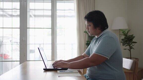 新常态一个男人在家里用笔记本电脑工作