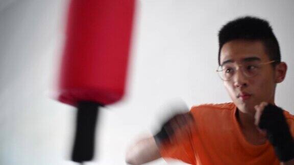一名亚洲华裔少年在隔离期间在卧室里练习拳击