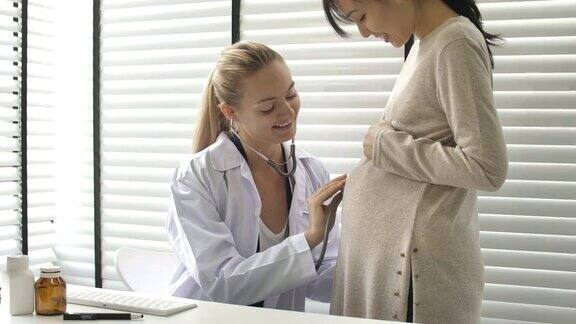 妇科医生在医生办公室用听诊器检查孕妇并与孕妇交谈