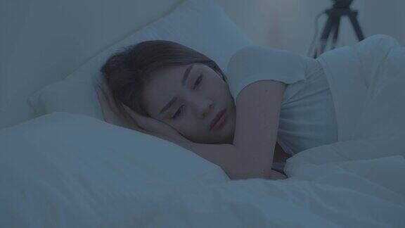 亚洲美丽的悲伤沮丧的女孩独自躺在床上的卧室有吸引力的不快乐的年轻女子感到孤独和沮丧的压力面对和思考生活问题在黑暗的夜房在家里
