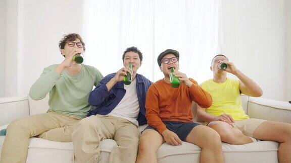 一群亚洲男性朋友一起在家里看电视上的体育比赛