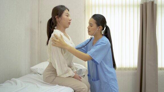 年轻的亚洲女医生治疗女性患者的背部疼痛女物理治疗师触摸背部检查脊柱损伤并用听诊器倾听患者的背部