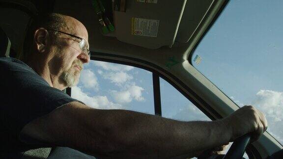 一个阳光明媚的日子一个50多岁的白人男子开着一辆卡车
