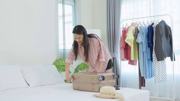 亚洲年轻美丽的女人准备衣服和打包手提箱有吸引力的女性游客旅行者感到快乐和放松而准备行李在床上准备旅行的假期旅行