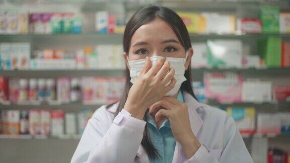 亚洲女性药剂师戴着外科口罩在现代药店的肖像covid-19和大流行