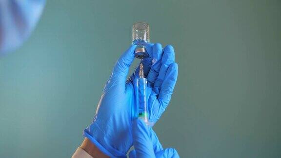 年轻的医生用注射器装满疫苗准备给病人注射疫苗戴医用口罩的医生站在蓝色背景上