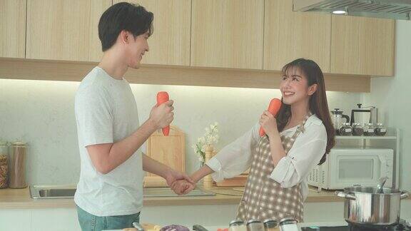 亚洲夫妇在家里的厨房里一边做饭一边唱歌一对情侣的浪漫场景