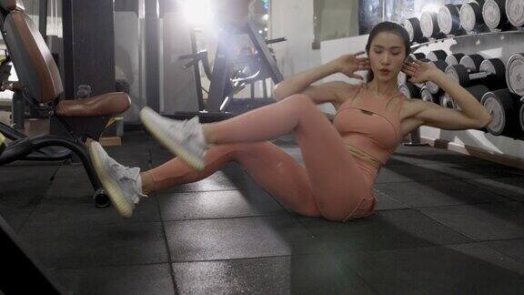 亚洲女人在健身房做仰卧起坐健康的女运动员在健身设施中进行核心力量锻炼