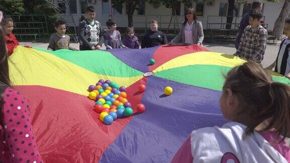 残疾儿童在玩五颜六色的降落伞和球