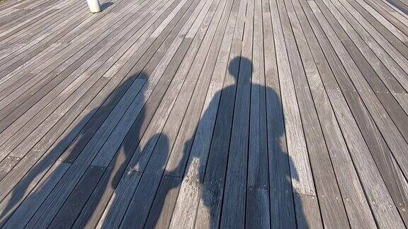父亲、母亲和孩子手拉手走在木地板上的影子