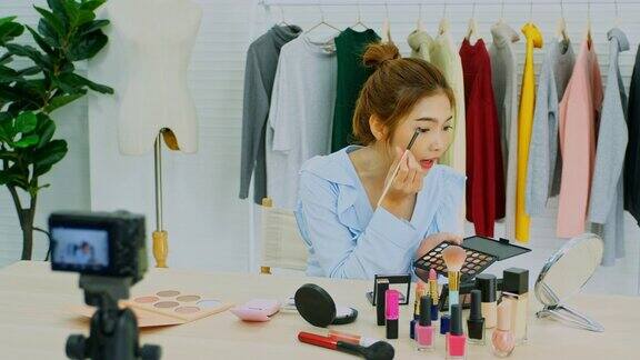 美丽博主视频博客展示化妆品坐在镜头前录制视频快乐美丽的年轻亚洲女性网红播送如何在社交网络