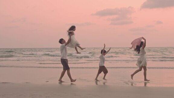 快乐的亚洲家庭享受日落时分在海滩上跑步