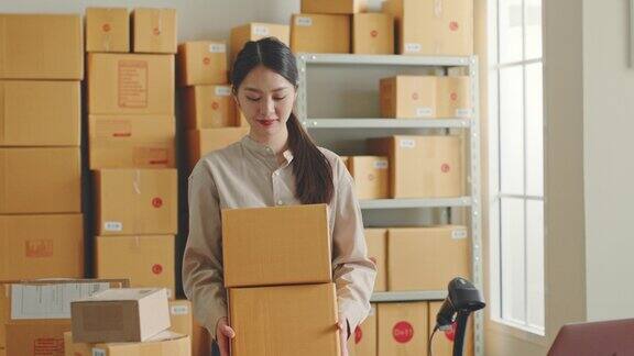 肖像自信的亚洲女性企业家在网上商店仓库工作在货架上的包裹盒子网上电子商务零售的小商业理念